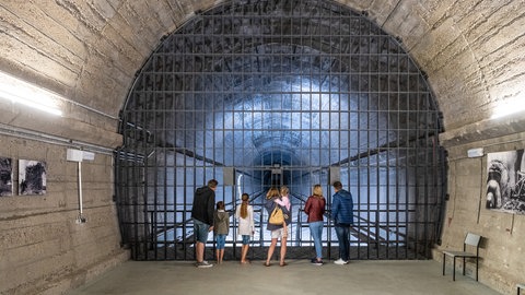 Besucher der Dokumentationsstätte Regierungsbunker stehen vor einen großen Tunnel, der durch die Berge führt.