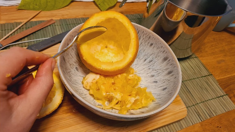 Den Inhalt vorsichtig mit einem Löffel aushöhlen oder mit einer Saftpresse ausdrücken. Das Fruchtfleisch vollständig entfernen.