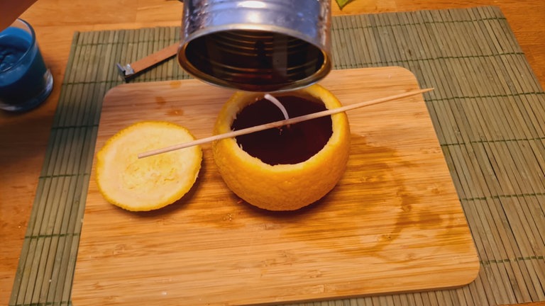 Das flüssige Wachs anschließend vorsichtig in die vorbereitete Orange gießen, bis die gewünschte Füllhöhe erreicht ist.