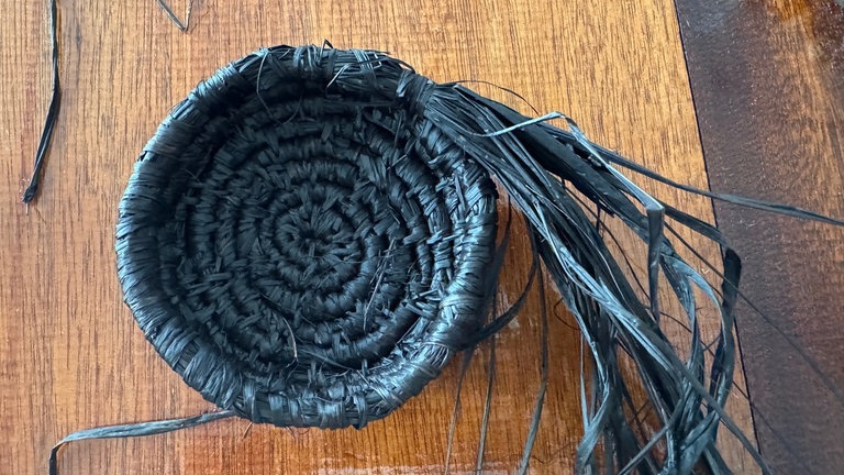 Dann die Bänder nach oben ziehen und wieder feststecken. Zum Schluss aus Bast eine Kordel rollen und an zwei gegenüberliegenden Stellen am oberen Körbchenrand fixieren.