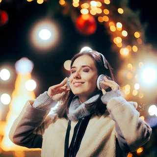 Frau hört Weihnachtsmusik über Kopfhörer