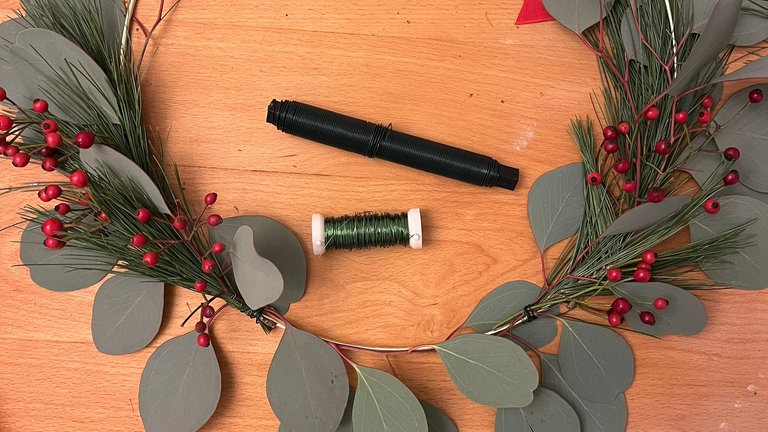 Einzelne Hagebuttenzweige zwischen das Grün legen und mit Draht fixieren. Sie sorgen für Farbe und einen winterlichen Akzent.