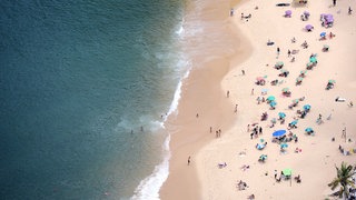 Menschen an einem Strand | Das sind die Reisetrends für euren Urlaub in 2026
