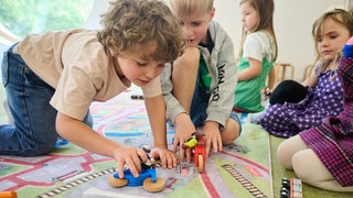 Eine Gruppe Kinder spielt auf einem Spielteppich | Das sind die Spielzeug-Trends 2025