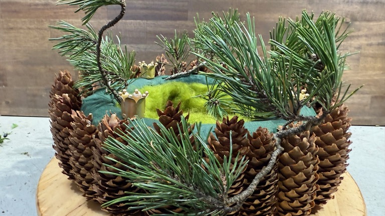 Der Kranz wird kreisförmig im Uhrzeigersinn mit Kiefergrün oder anderem Grün gesteckt. 