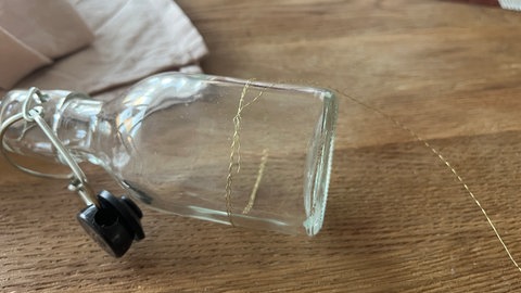 3 Meter Draht abschneiden und den Anfang um eine kleine Flasche wickeln. Das Ende wird einfach miteinander verdreht.