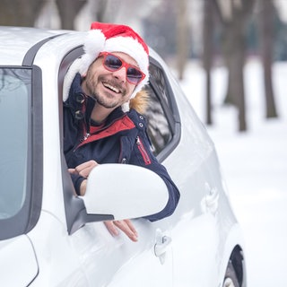 Mann fährt mit Weihnachtsmütze mit dem Auto