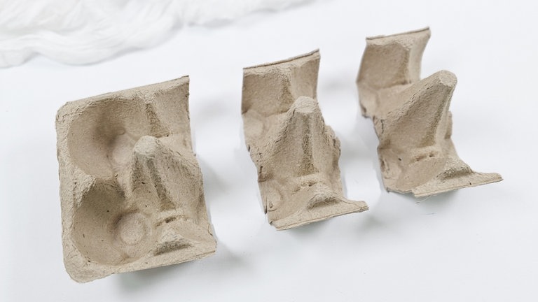 Den Karton so zuschneiden, dass drei Spitzen herausgeschnitten werden können.