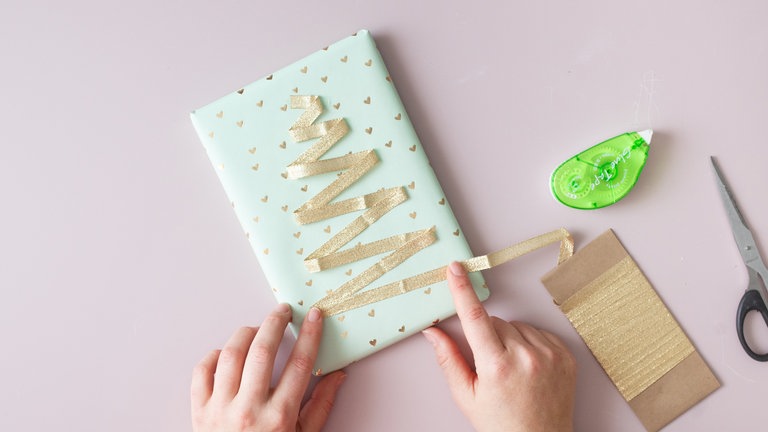 An jeder Ecke einen Klebepunkt setzen bzw. mit dem Kleberoller rollen. Unten das Band abschneiden und mit Klebestreifen sichern. 