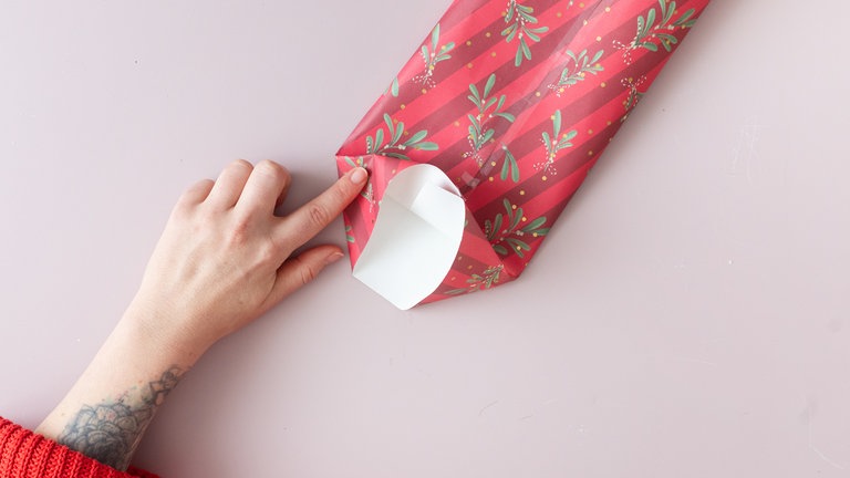 Die Querfalte an den Seiten nach innen drücken, sodass zwei Dreiecke entstehen.