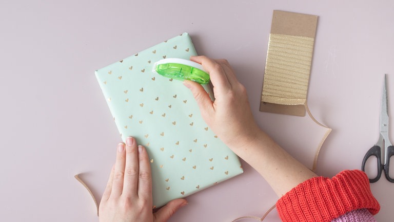 Das lange Geschenkband an einem Ende fixieren