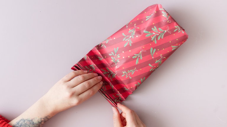 Die obere Öffnung flach hinlegen, dann 4-6 Falten nach vorn und hinten legen - wie eine Ziehharmonika.