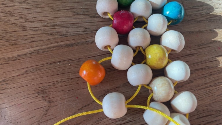 Ab jetzt wieder auf die gleiche Weise Vierer-Kreise bilden, dabei aber mit einer Kordel immer in die äußere Perle der vorherigen Kreise gehen, damit ein zusammenhängendes Muster entsteht. 