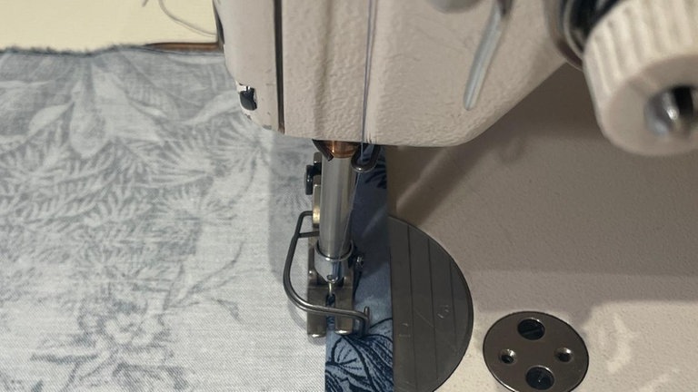 Anschließend wird die Hälfte des eben Umgebügelten nach innen eingeschlagen und schmalkantig mit Geradstich festgenäht. 