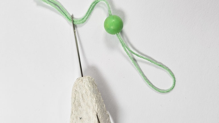 Mit der Nadel nun von oben durch die Eierkarton-Blüte stechen...