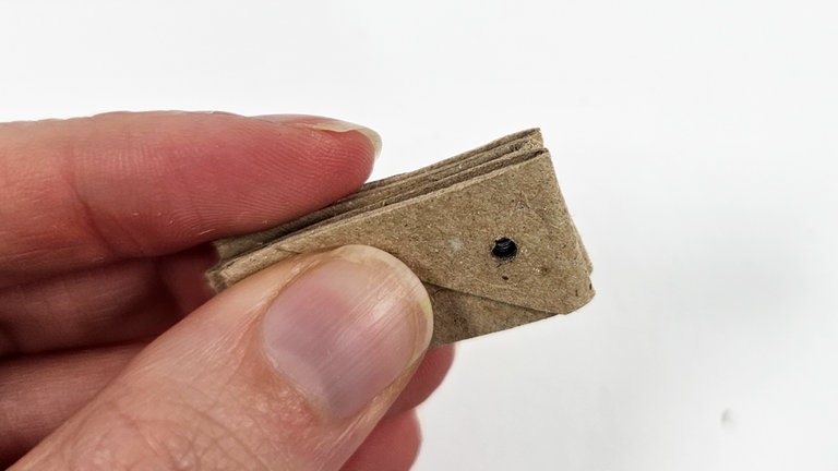 Die gefalteten Stücke bündig aufeinanderlegen und ein kleines Loch hineinstanzen.