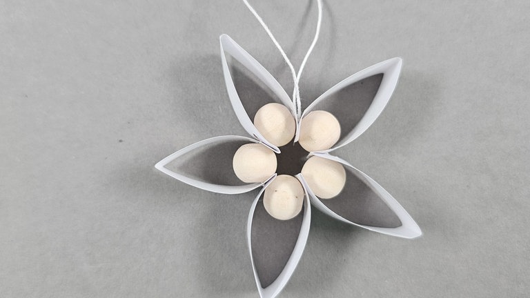 Etwas oberhalb einen Knoten zur Aufhängung in die Schnur knoten und überstehende Fäden abschneiden.