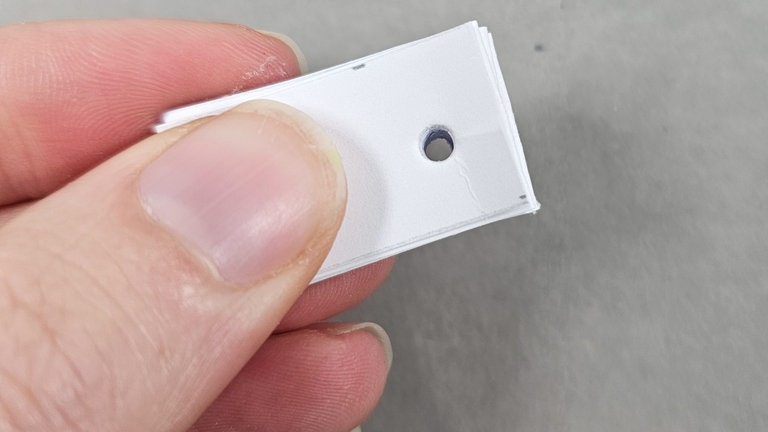 In den gefalteten Papierstreifen ein kleines Loch durch alle Schichten hindurch stanzen.