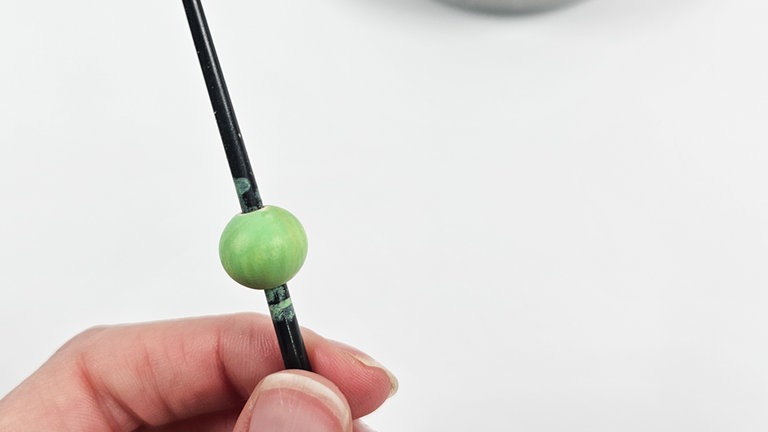 Anschließend die Holzperlen (eine pro Schneeglöckchen) in einem Grünton anmalen, dabei versuchen möglichst einen Ton zu treffen, der farblich zur Schnur passt.