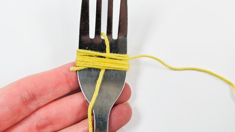 Das Garn straff um den breiten Teil der Gabel wickeln. 