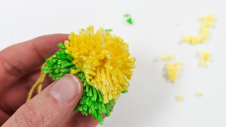 Den Pompon gleichmäßig rund schneiden.