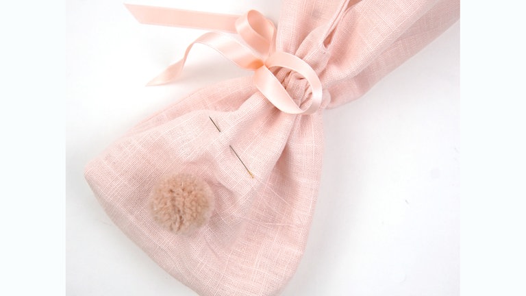 Den Pompon von Hand an das Hasen-Beutelchen nähen. 