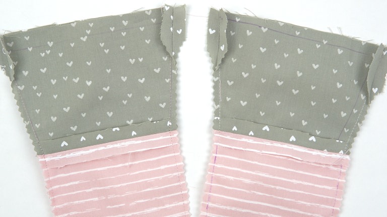 Die Nahtzugaben auf 5 mm zurückschneiden bis auf folgende Ausnahme:  Entlang der Wendeöffnung und am oberen Rand (ca. 3 cm) Nahzugabe stehen lassen und diese auseinanderbügeln. 