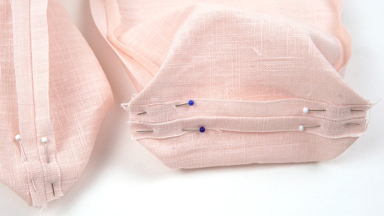 Die Nahtzugaben auseinanderbügeln. Die Stofflagen am Boden auseinanderziehen, die Kanten der inneren Ecken an den Böden bündig aufeinanderlegen und heften. 