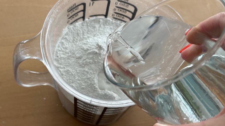 Entsprechend der Anleitung auf der Verpackung des Pulvers Wasser hinzugeben.