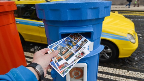 Ein Mann wirft auf Madeira Postkarten in einen Briefkasten.