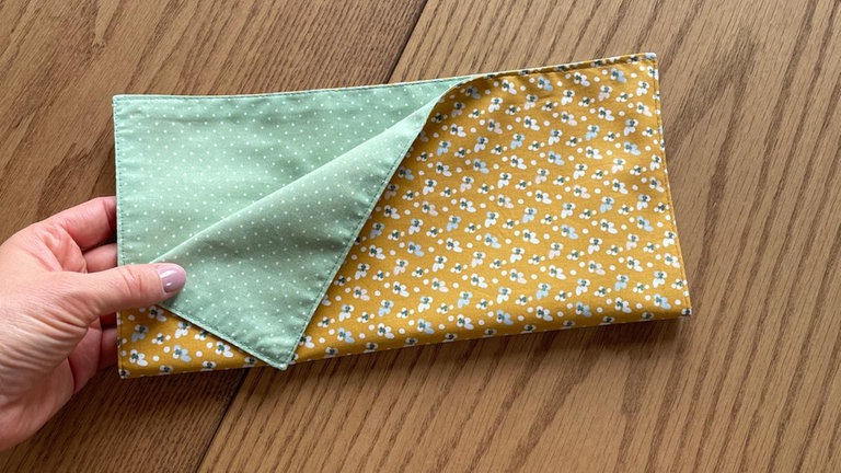 Das quadratische Stoffstück einmal mittig falten, sodass ein Rechteck entsteht. 