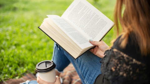 Frau liest draußen ein Buch
