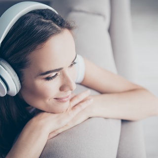 Frau hört mit auf der Couch mit den Kopfhörern