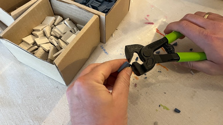 Zunächst die Fliesen mit der Zange in Stücke brechen. 