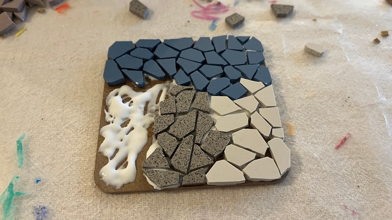 Den Kleber großzügig auf die erste Ecke oder sogar auf die Hälfte der MDF-Untersetzer auftragen. 