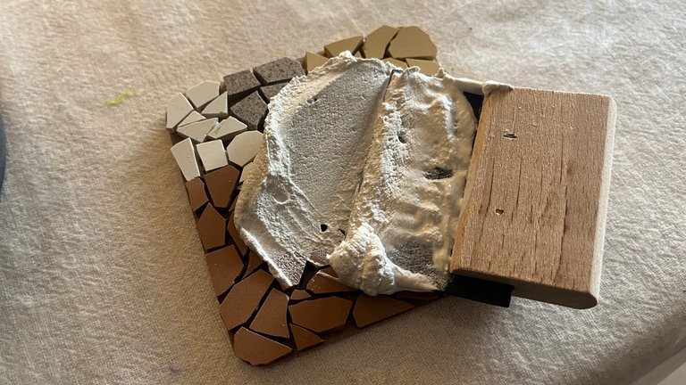 Fugenmasse gleichmäßig auf dem Untersetzer verteilen.