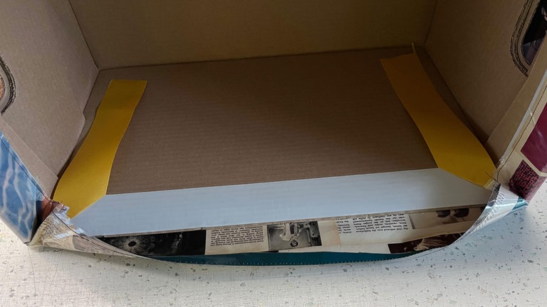 Die Papierrückseite des Klebebandes wird entfernt, zunächst werden nacheinander die beiden schmalen Seiten oben eingeschlagen, danach die langen Seiten. Die Ecken werden in Falten gelegt.