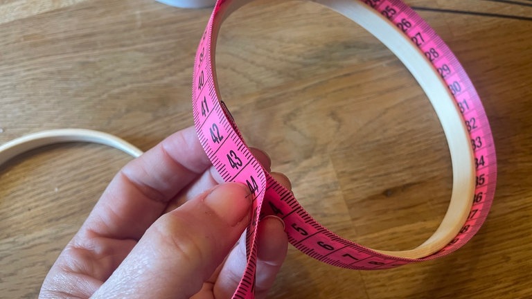 Den Stickrahmen auseinandernehmen und vom inneren Holzring den äußeren Umfang mit dem Maßband abmessen.