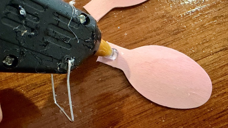 Wenn alle Löffel geschnitten sind, kann es ans Kleben des Kranzes gehen. Die Löffel mit Heißkleber zusammenkleben, damit sich eine Art Blüte ergibt.