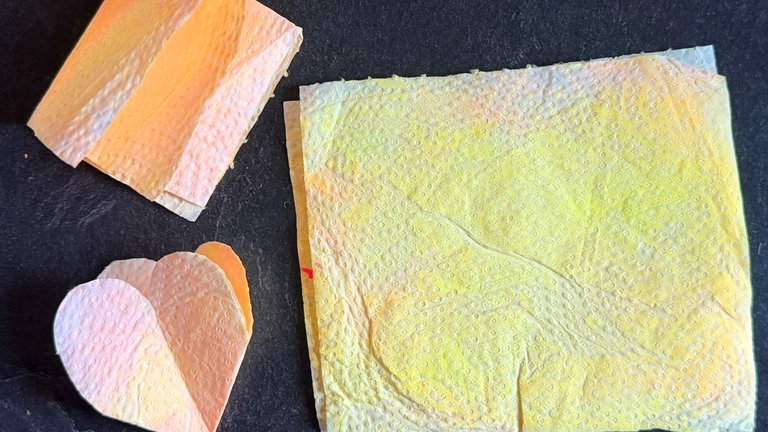 Das getrocknete Papier zweimal in der Mitte falten und ein kleines Herz daraus ausschneiden. 