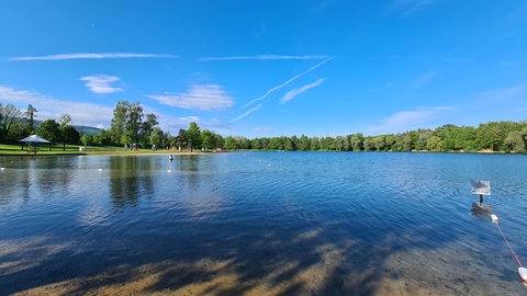 Badesee Buchtzig in der Region Karlsruhe mit Liegewiesen, Spielplatz und blauem Himmel.