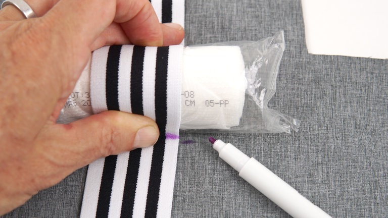 Für die höheren und größeren Utensilien folgendermaßen vorgehen: Das Gummiband über das Utensil spannen. Die Nahtstelle mit einem Markierstift auf dem Gummiband und dem Grundstoff anzeichnen.