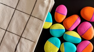 Bemalte Steine liegen neben einem Säckchen mit Spielfeldern