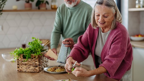 Ein älteres Paar kocht gemeinsam ein Pasta-Gericht - vielleicht Cacio e Pepe?