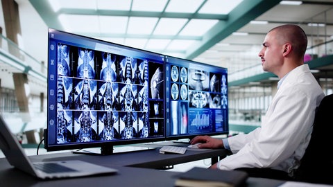 Ein Arzt sieht sich Aufnahmen einer Wirbelsäule auf dem Computer an. Künstliche Intelligenz kann bereits jetzt die Diagnose mit solchen Aufnahmen revolutionieren.
