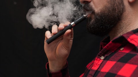 Person raucht Vape. Neue synthetische Drogen sind als Forschungschemikalien frei verkäuflich.