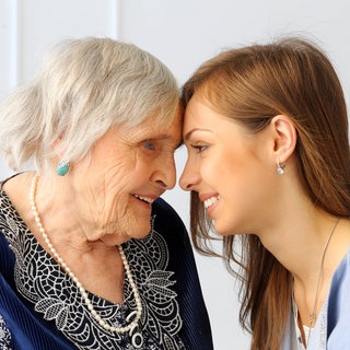 Eine Seniorin und eine junge Frau Stirn an Stirn: Alte Menschen riechen anders als junge, denn im Alter verändert sich die Haut. Die Fette, die wir über die Talgdrüsen ausscheiden, verändern sich. Die Haut verliert an Feuchtigkeit und ist daher im Alter trockener. Damit ändert sich auch die Zusammensetzung der Düfte, die unser Körper und unsere Duftzellen abgeben.
