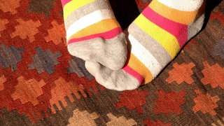 Füße in wärmenden Ringelsocken: Neigen Frauen eher zu kalten Füßen als Männer?