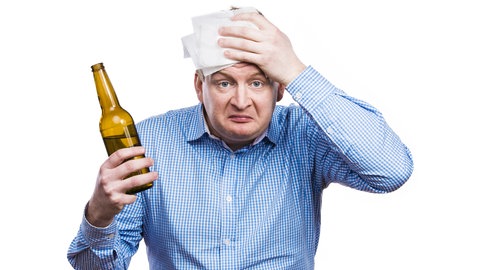 Mann mit Bierflasche in der Hand hat Kopfschmerzen: Ob Bier oder Wein ist egal: Wer einen Kater vermeiden will, muss auf die Menge des Alkohols achten
