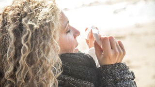 Frau beim Winterspaziergang putzt sich die Nase